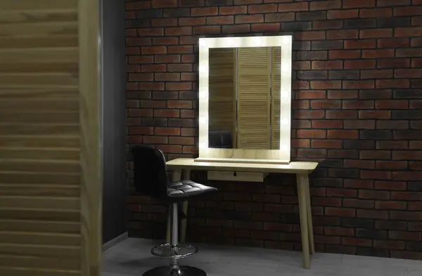 Mirror with light bulbs, table and chair in makeup room