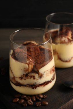 Bardakta nefis tiramisu ve tahtanın üzerinde kahve çekirdekleri, yakın plan.