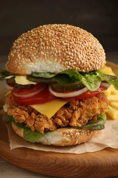 Delicious burger with crispy chicken patty on wooden table, closeup