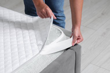 Kadın yatağın içine koruyucu koyuyor, yakın plan.