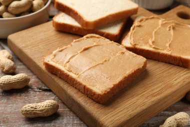 Lezzetli fıstık ezmeli sandviçler ve fıstıklar ahşap masada, yakın plan.