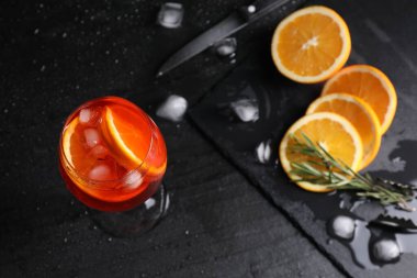 Üzerinde portakal dilimleri, buz küpleri ve biberiye olan bir bardak nefis Aperol spreyli kokteyl.