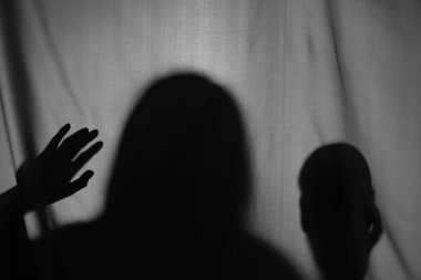 Gri kumaşın arkasında kafatası olan ürkütücü bir hayalet silueti.