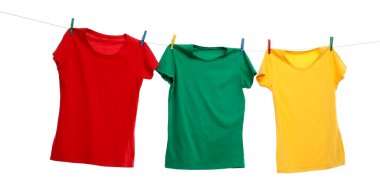 Beyaz arka planda çamaşır ipinde kuruyan farklı parlak tişörtler.