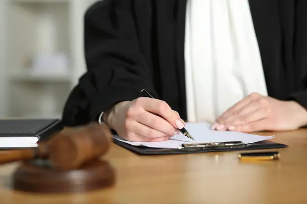 Judge working with document at table indoors, closeup