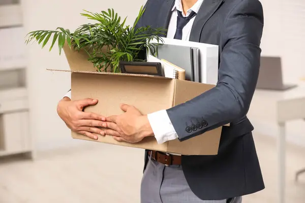 Unemployment problem. Man with box of personal belongings in office, closeup