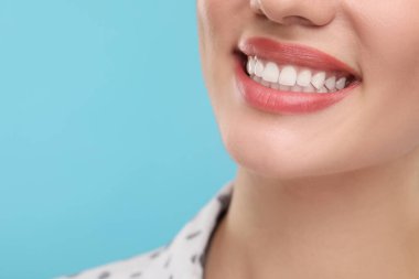 Temiz dişli bir kadın açık mavi arka planda gülümsüyor, yakın plan. Metin için boşluk