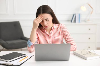 İş yerinde baş ağrısı çeken genç bir kadın.