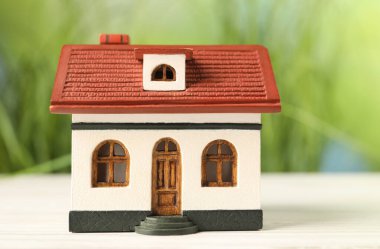 İpotek konsepti. Beyaz ahşap masadaki ev modeli bulanık yeşil arka plana karşı