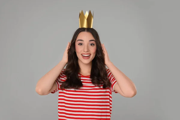 Beautiful young woman with princess crown on grey background