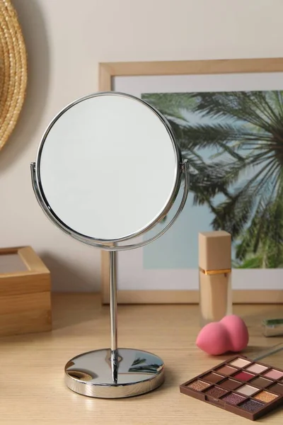Mirror, picture and makeup products on wooden dressing table