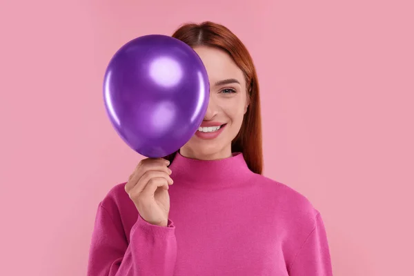 Happy woman with purple balloon on pink background