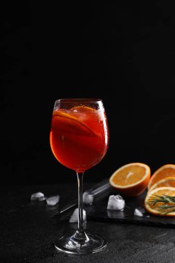 Bir bardak lezzetli Aperol spreyli kokteyl portakal dilimleri ve buz küpleriyle siyah arka planda, metin için yer var.
