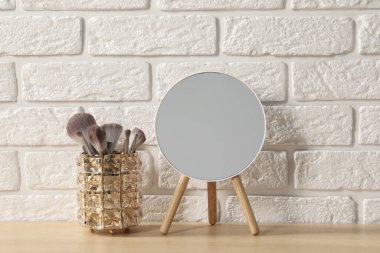 Odadaki ahşap tuvalet masasında ayna ve makyaj fırçaları.