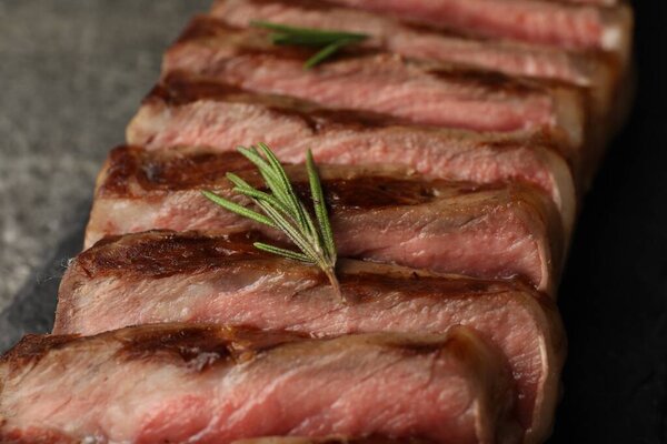 Delicious grilled beef steak with rosemary on table, closeup