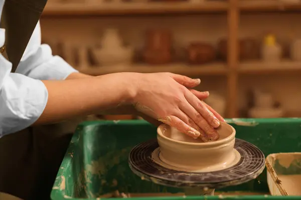 Clay crafting. Woman making bowl on potter\'s wheel in workshop, closeup