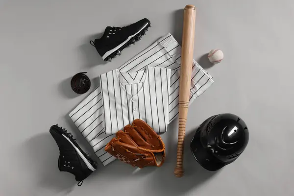 Baseball uniform and other sports equipment on white background, flat lay