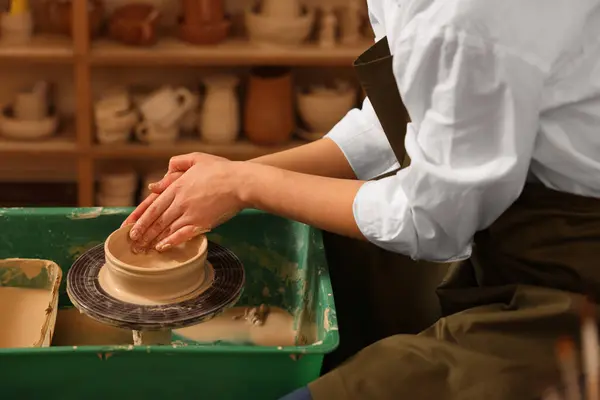 Clay crafting. Woman making bowl on potter\'s wheel in workshop, closeup