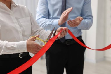 Kırmızı kurdeleyi içeride makasla kesen kadın, yakın plan.