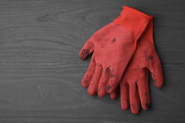 Gri ahşap masada, üst manzaralı bir çift kırmızı bahçe eldiveni. Metin için boşluk