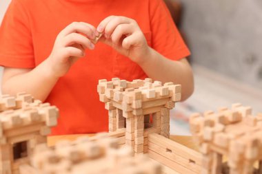 Küçük çocuk odasındaki masada ahşap inşaatla oynuyor, yakın plan. Çocuk oyuncağı