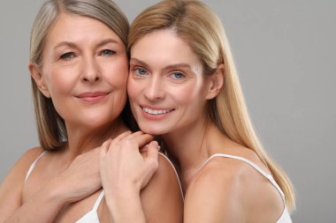 Gri arka planda sağlıklı ciltli güzel kadınlar.