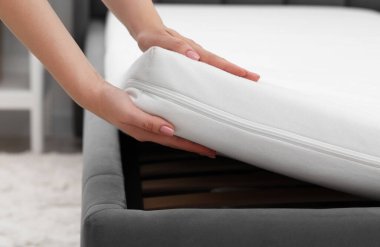 Yatağa yeni yumuşak bir yatak koyan kadın, yakın plan.