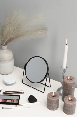Aynalı makyaj masası, kozmetik ürünler ve makyaj odasında mum yakma.