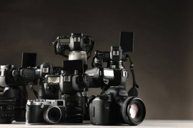 Beyaz masadaki modern kameralar koyu arkaplan karşısında
