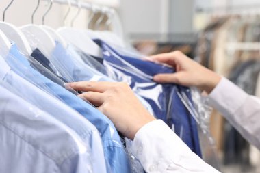 Kuru temizleme servisi. Kadın gömleğini plastik torbaya koyuyor, kapalı mekandan, yakın plan.