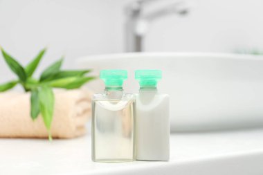 Banyodaki beyaz tezgahta mini kozmetik ürünleri şişeleri.