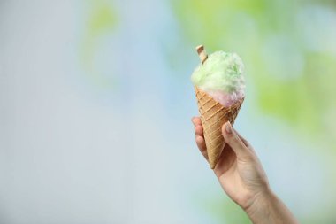 Arka planda pamuk şekerli waffle külahı tutan kadın, yakın plan. Metin için boşluk