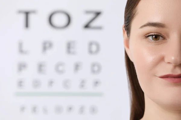 Young woman against vision test chart, closeup