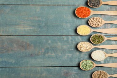 Düz kompozisyon, farklı türde baklagiller ve tahıllar mavi ahşap masa üzerinde, yazı için boşluk. Organik taneler