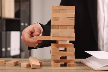 Jenga oynuyorum. Kapalı alandaki masadaki ahşap bloğu kuleden kaldıran adam.