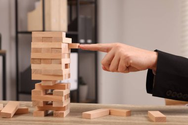 Jenga oynuyorum. İçerideki masada tahta blokları olan bir adam kule inşa ediyor, yakın plan.