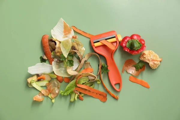 緑の背景に新鮮な野菜とピーラーの皮 フラットレイ — ストック写真