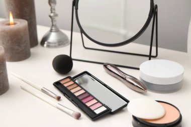 Ayna, kozmetik ürünleri ve tuvalet masasında yanan mumlar.