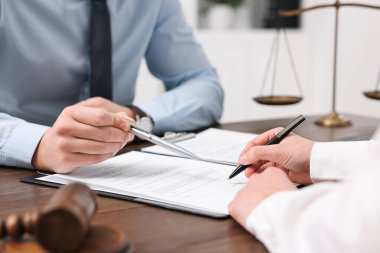 Ofisteki ahşap masada evraklarla çalışan avukatlar, yakın plan.