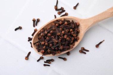 Beyaz karolar üzerinde aromatik kurutulmuş karanfil tomurcukları ile kaşık, üst görünüm