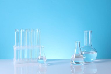 Laboratuvar analizi. Açık mavi arka planda cam test tüpleri ve mataralar