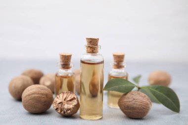 Nutmeg temel yağı, fındık ve yapraklar açık gri masada, yakın plan