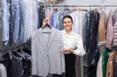 Kuru temizleme servisi. İçeride ceketli, askılık tutan mutlu işçi.