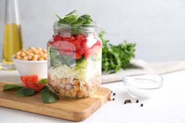 Beyaz masada cam kavanozda sağlıklı salata.