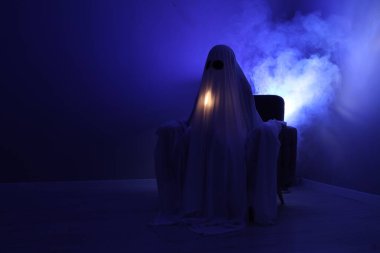 Ürkütücü hayalet. Mavi ışıkta koltukta oturan çarşaflı kadın, metin için boşluk.