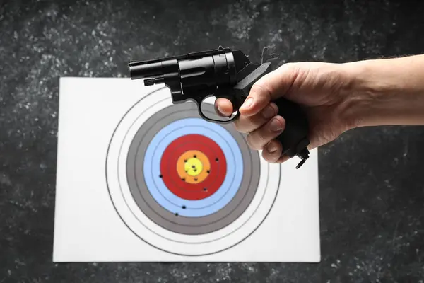 Man with handgun near shooting target, closeup