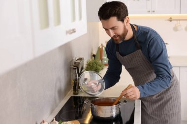 Adam mutfaktaki ocağın üstünde domates çorbası pişiriyor.