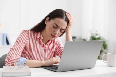 İş yerinde baş ağrısı çeken bir kadın.