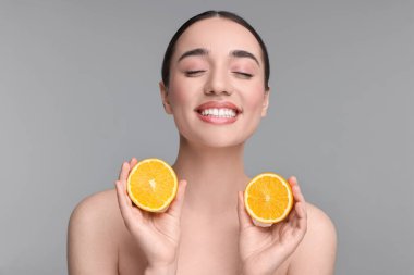 Gri arka planda turuncu parçaları olan güzel bir genç kadın.