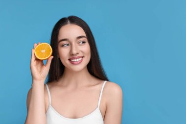 Açık mavi arka planda turuncu parçası olan güzel bir genç kadın. Metin için boşluk